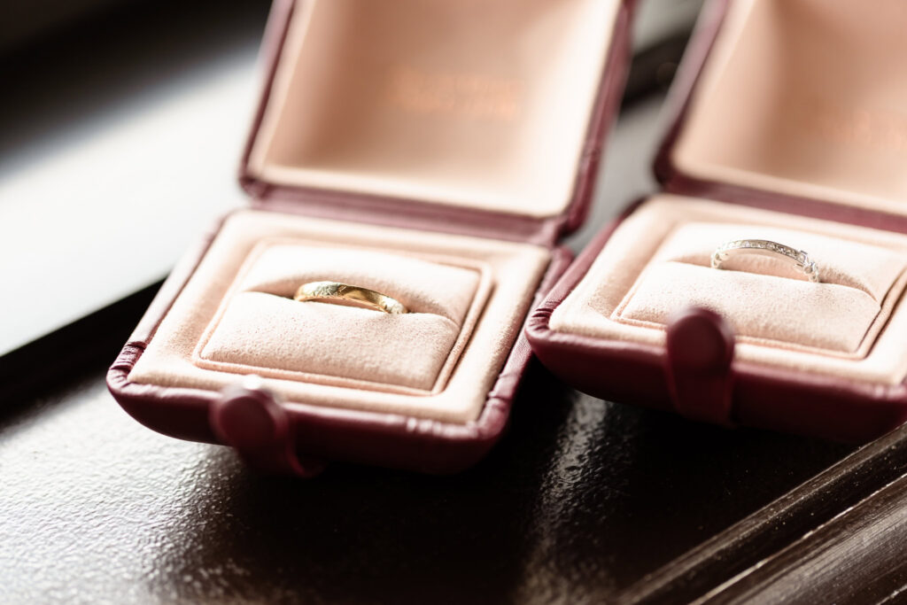 Antique wedding rings displayed in velvet boxes during a 1920s wedding on Long Island featuring period-accurate details.
