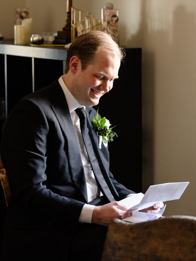 Groom smiling while reading a heartfelt letter before the wedding.