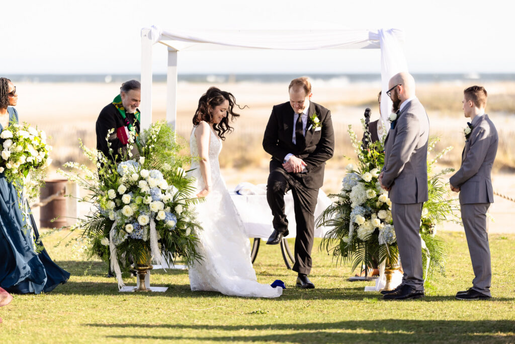 Couple participating in a wedding tradition during a 1920s wedding Long Island ceremony by the beach.