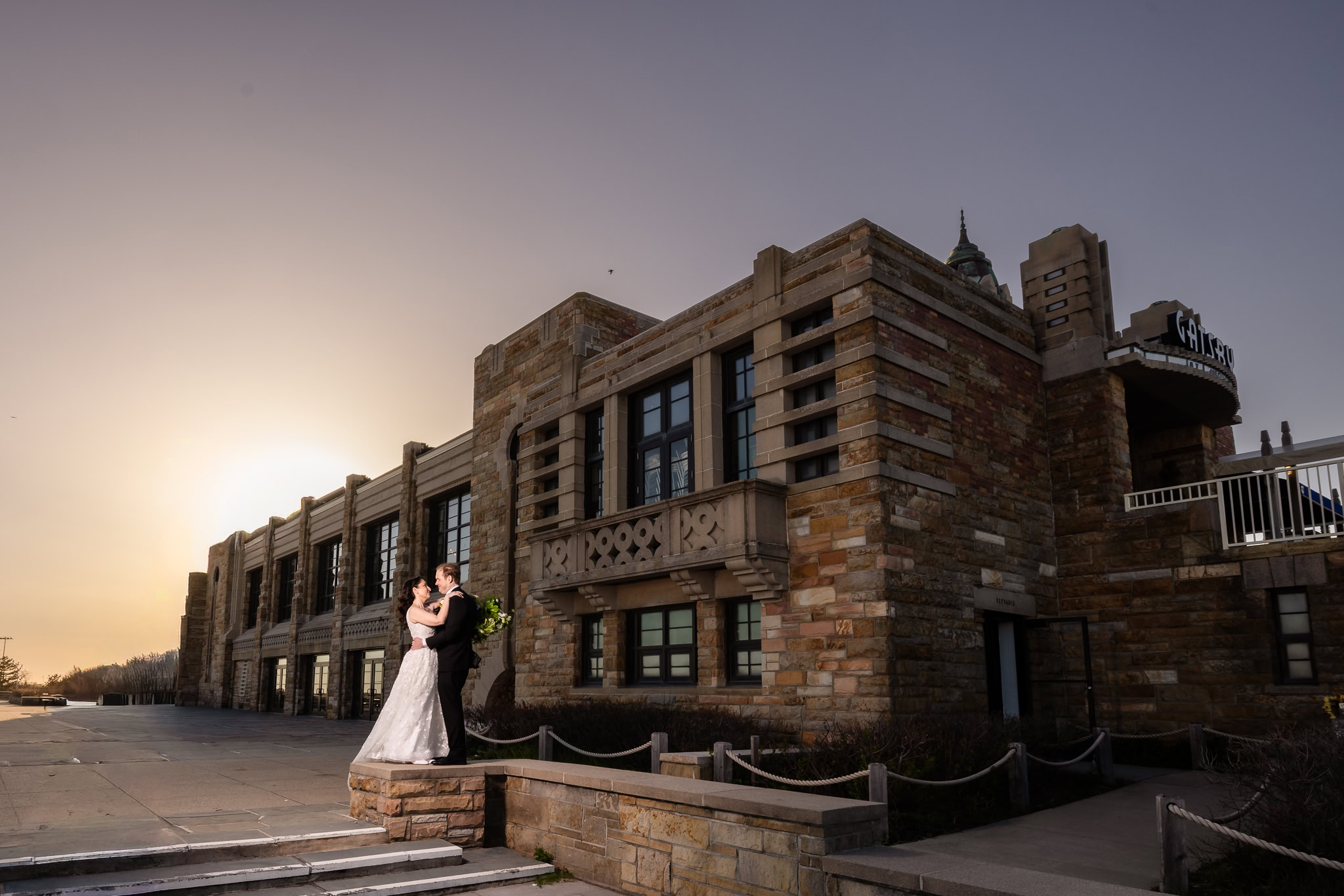Newlyweds embracing outside an Art Deco-inspired venue at sunset during a 1920s wedding Long Island celebration.