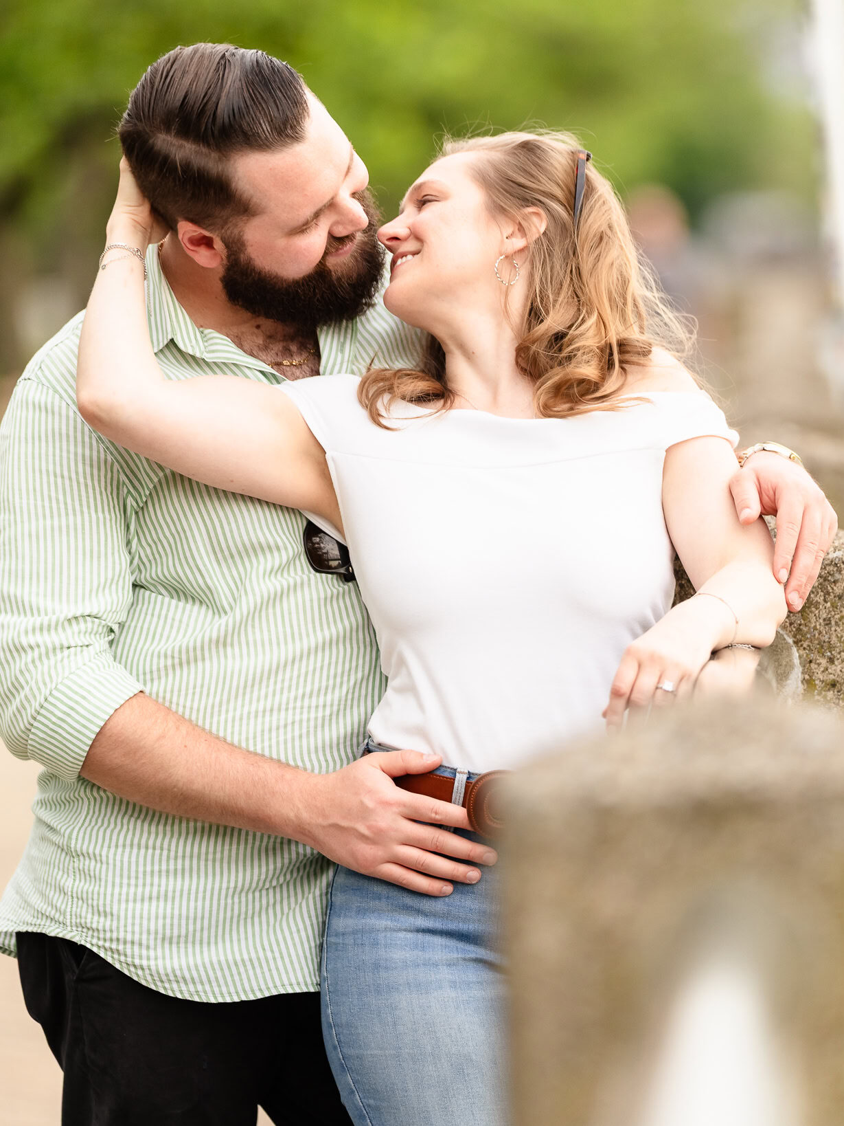 Engaged couple embracing along the Roosevelt Island waterfront with soft evening light and East River views.