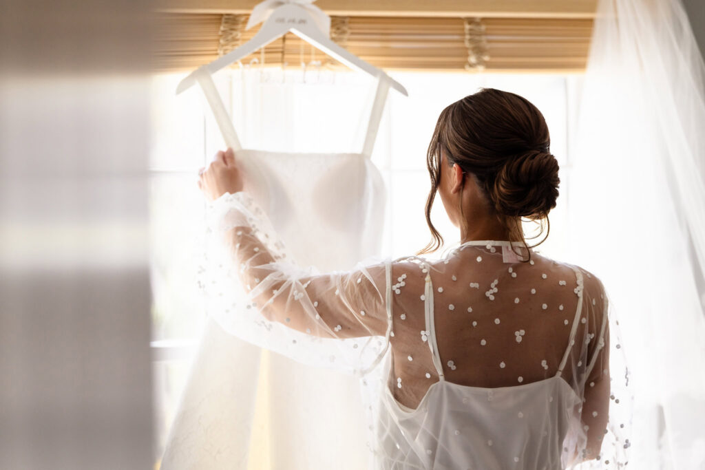 Ashley admires her wedding dress during bridal preparations before her Heritage Club wedding on Long Island.