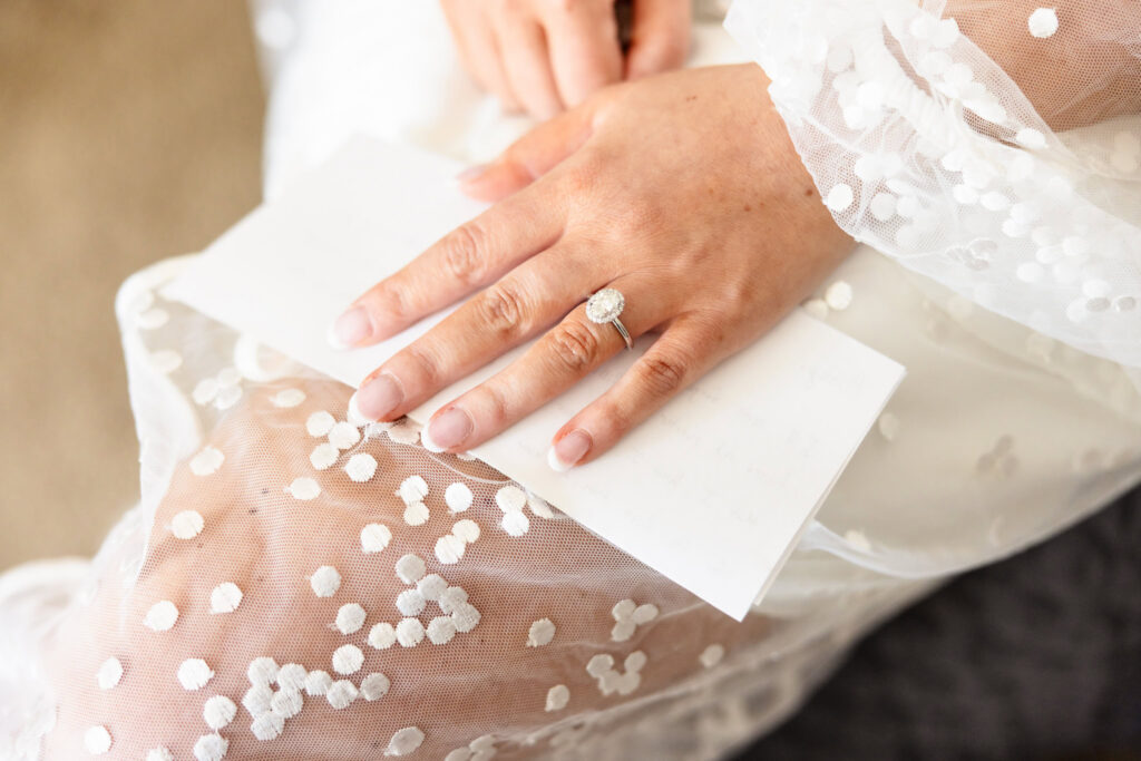Close-up of the bride's engagement ring resting on a handwritten letter during wedding day preparations.