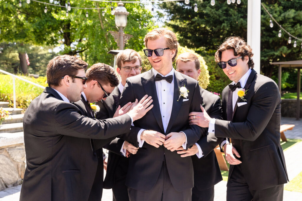 Kyle laughs with his groomsmen during wedding party portraits at The Heritage Club at Bethpage.