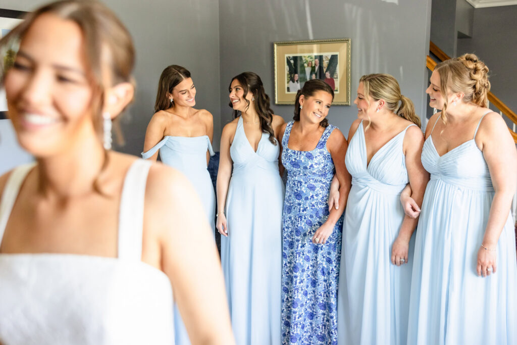 Ashley shares a joyful moment with her bridesmaids and family during wedding morning preparations at her childhood home.