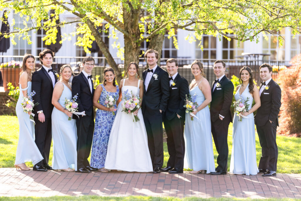 Ashley and Kyle pose with their wedding party outdoors at The Heritage Club at Bethpage following their ceremony.