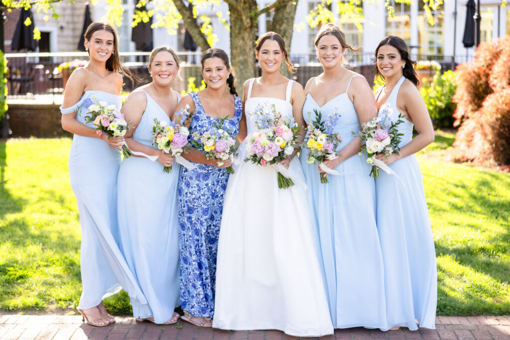 Ashley stands with her bridesmaids and maid of honor, holding pastel floral bouquets at The Heritage Club at Bethpage.