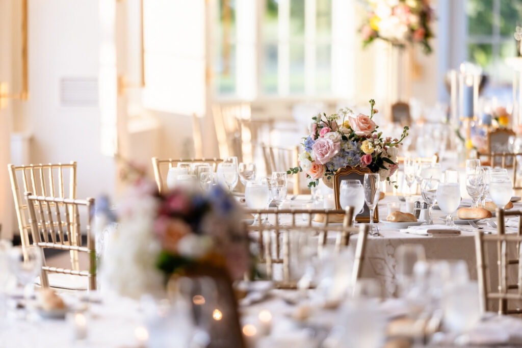 Pastel floral centerpiece displayed on a reception table at The Heritage Club at Bethpage with candlelight and elegant place settings.