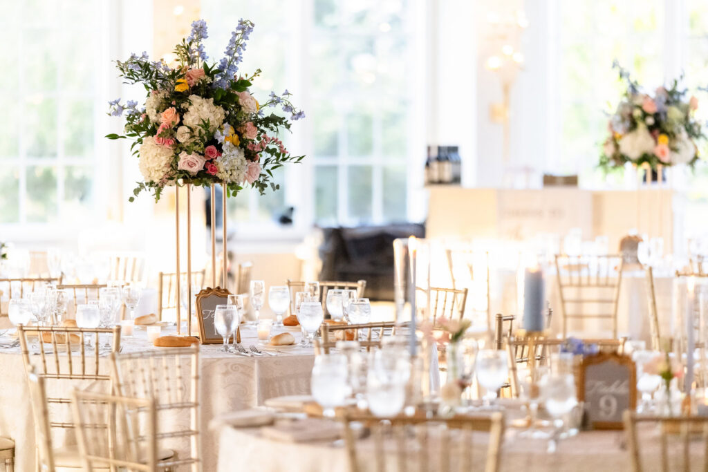 Tall floral centerpiece with pastel blooms and greenery decorating a reception table at The Heritage Club at Bethpage.