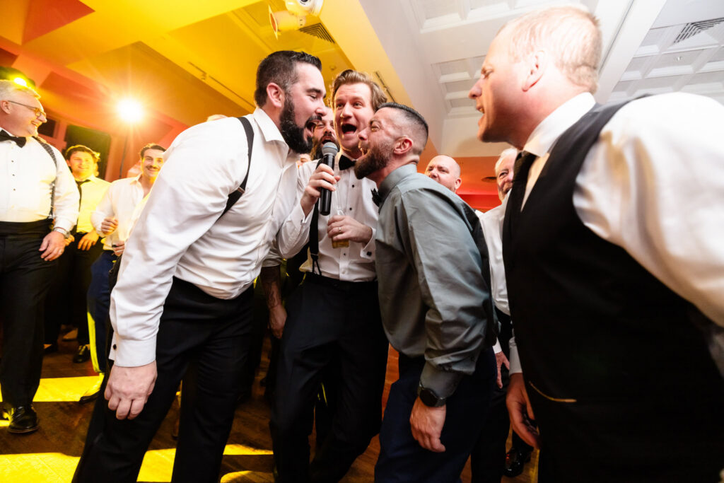Kyle and guests sing along to a favorite song on the dance floor during the wedding reception at The Heritage Club at Bethpage.
