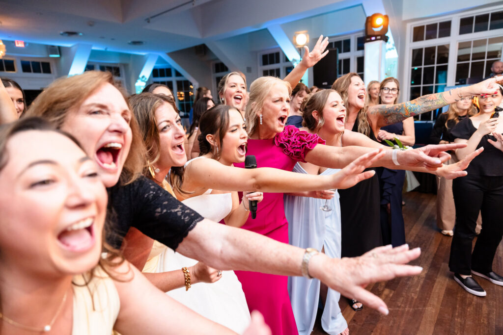 Ashley, family members, and wedding guests sing and celebrate together on the dance floor at The Heritage Club at Bethpage reception.