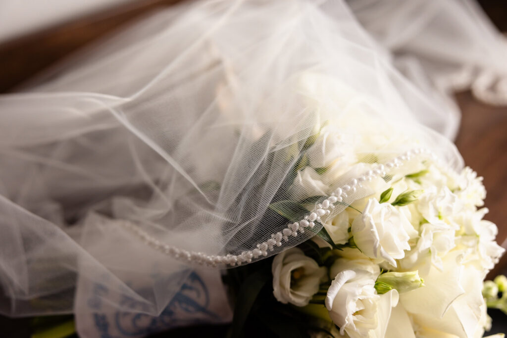 Bridal bouquet of white roses and calla lilies wrapped beneath a pearl-edged veil before a Huntington Crescent Club wedding.