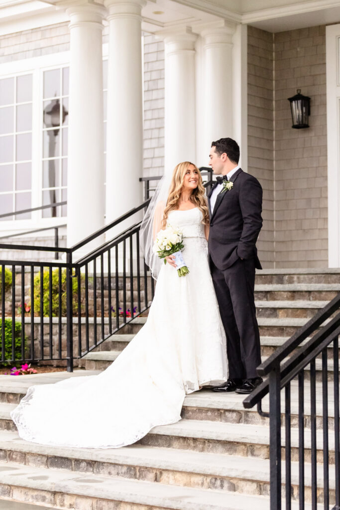 Newly married couple standing together on the front steps during their Huntington Crescent Club wedding portraits.