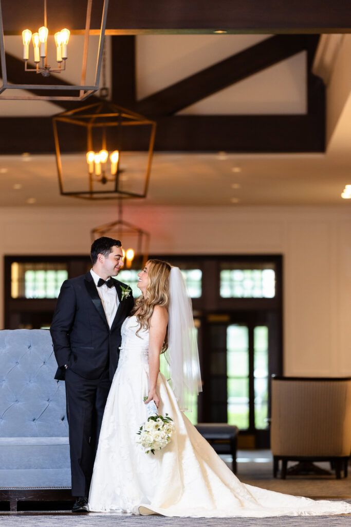 Bride and groom sharing a joyful portrait inside the elegant lobby at their Huntington Crescent Club wedding.
