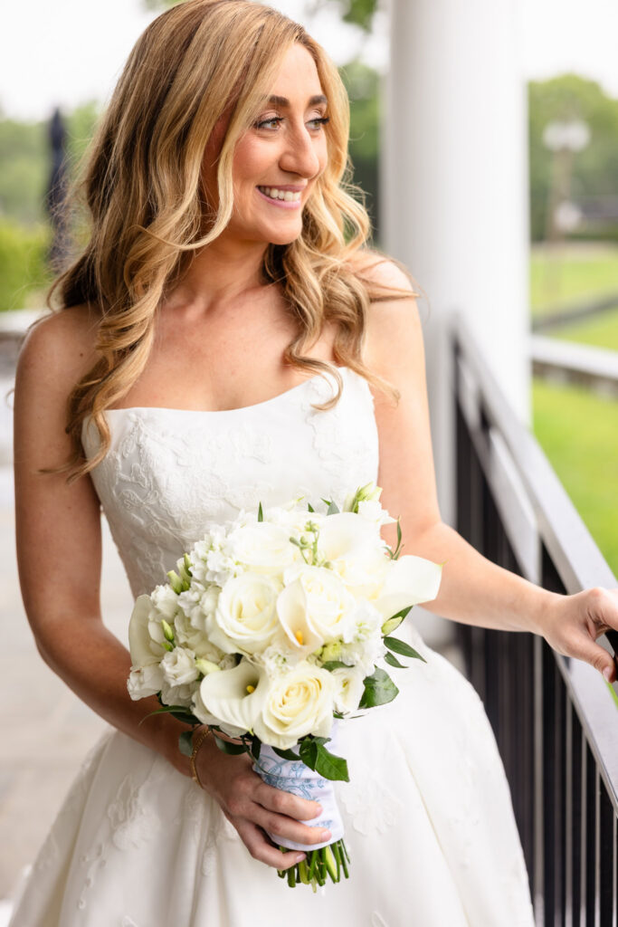 Classic bridal portrait with the bride holding a white bouquet on the veranda during her Huntington Crescent Club wedding.