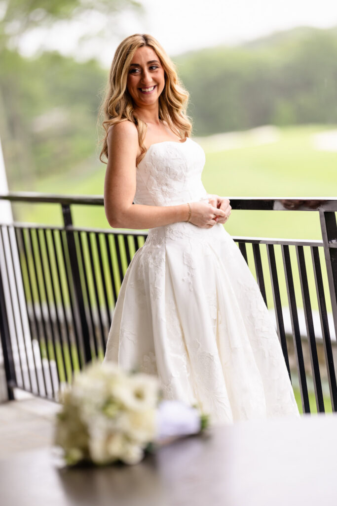 Smiling bride posing on the covered terrace before celebrating her Huntington Crescent Club wedding reception.