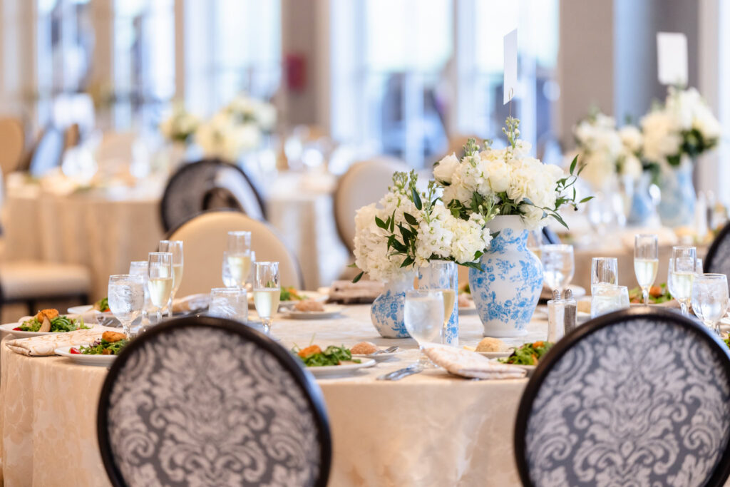Reception tables decorated with blue and white floral centerpieces.