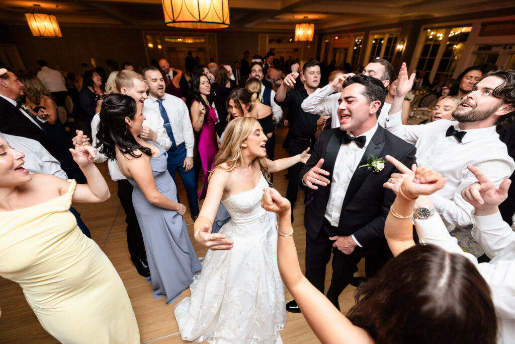 Bride and groom dancing with family and friends during a lively Huntington Crescent Club wedding reception.