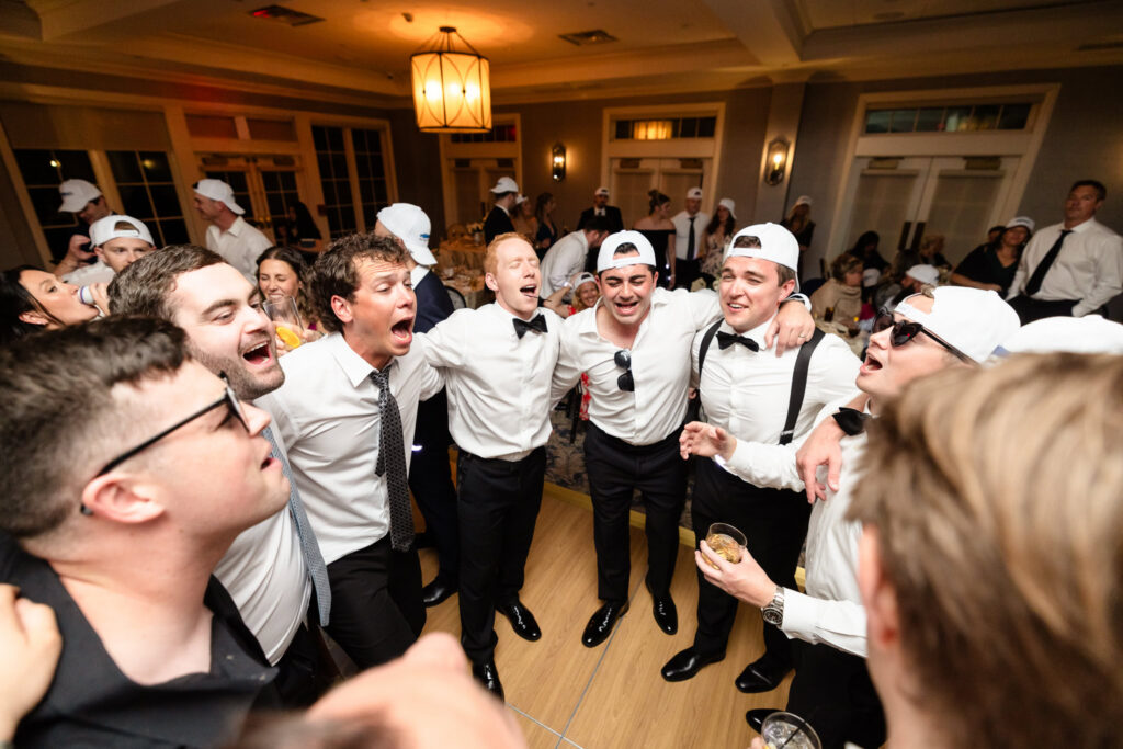 Groomsmen singing together with arms around each other during the reception.