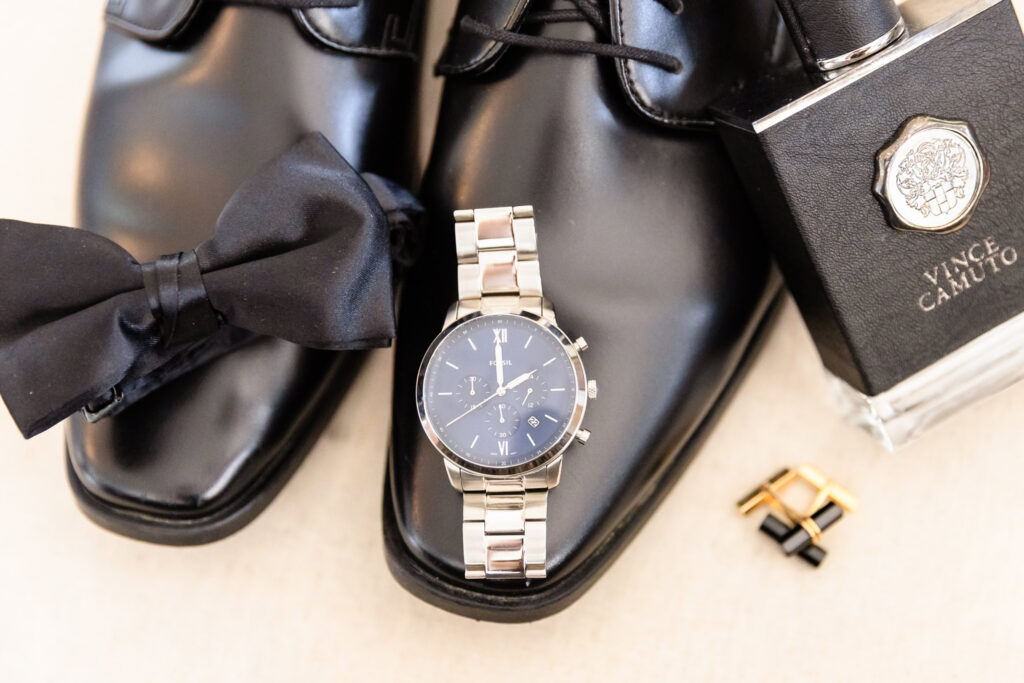 Groom accessories including watch, shoes, bow tie, and cufflinks for a spring wedding at Land's End.
