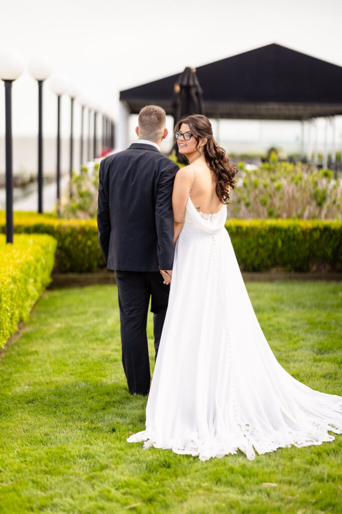 Bride looks back and smiles while walking with her groom during a spring wedding at Land's End.