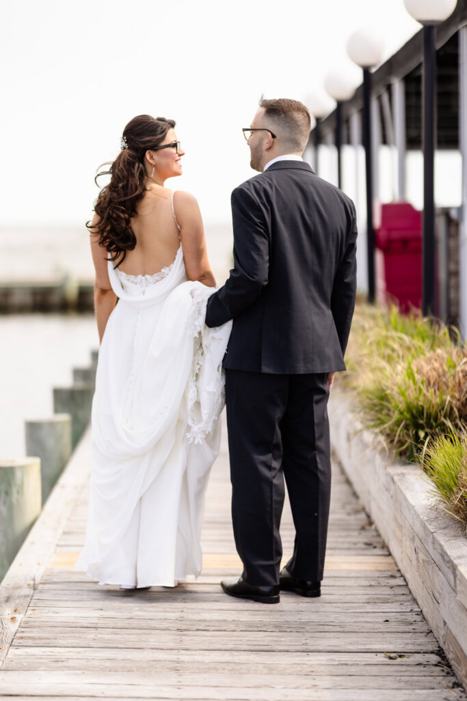 Bride and groom walking together on the waterfront boardwalk during a spring wedding at Land's End.