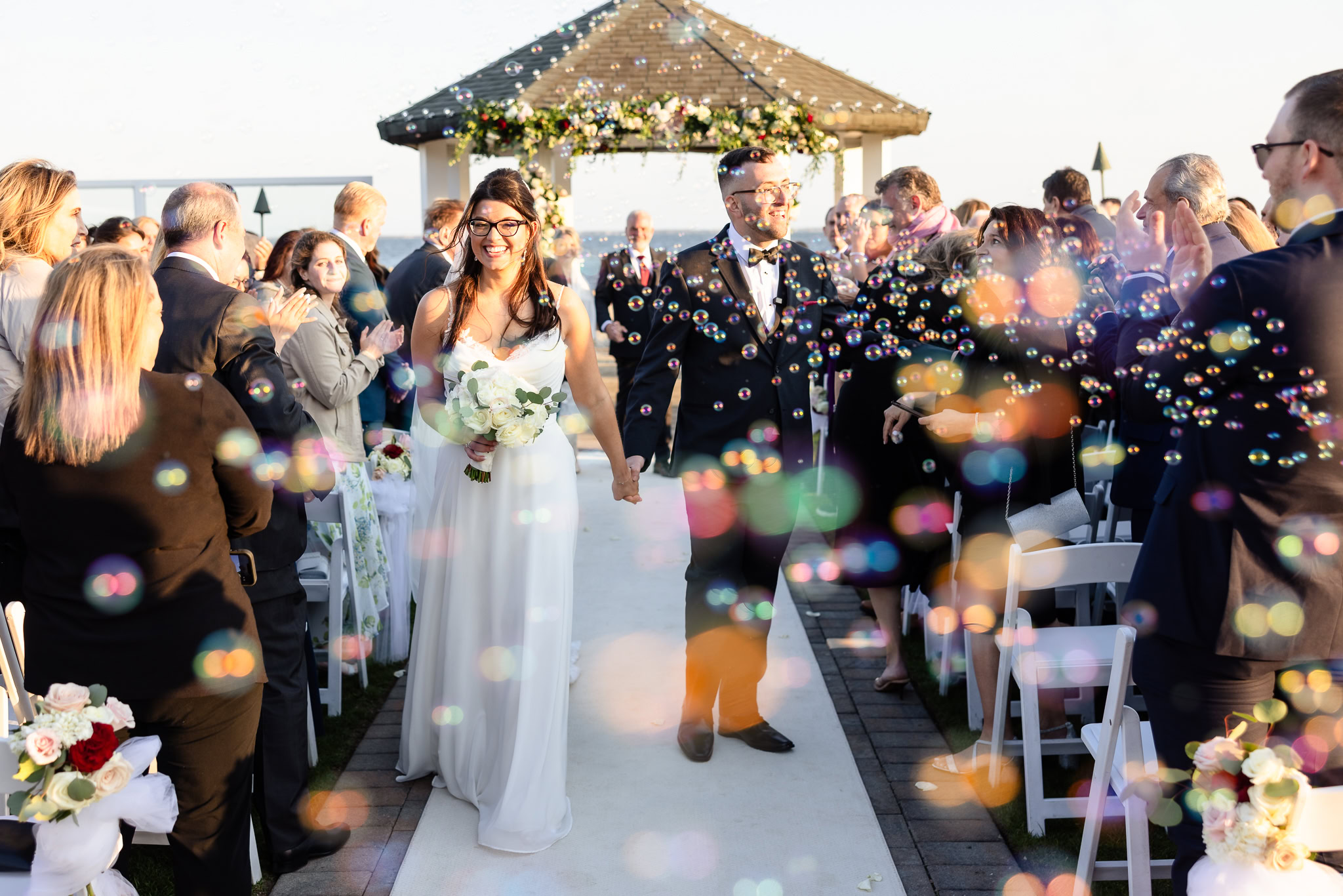 Newly married couple walking down the aisle through bubbles after their spring wedding at Land's End ceremony.