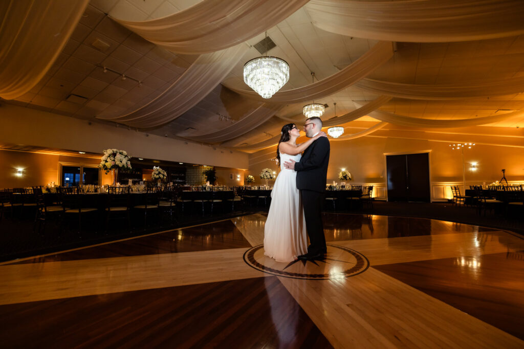 Bride and groom sharing their first dance in the softly lit ballroom at Land's End.