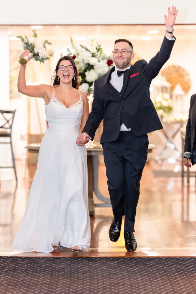 Bride and groom making an enthusiastic grand entrance into their reception at Land's End.