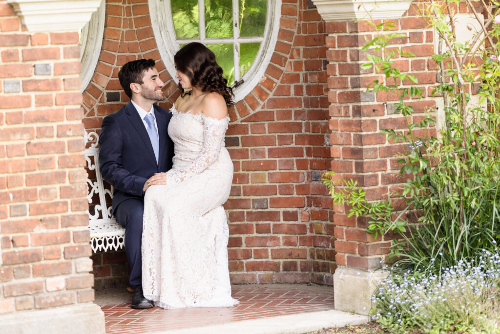 Couple seated together beneath a brick garden pavilion.