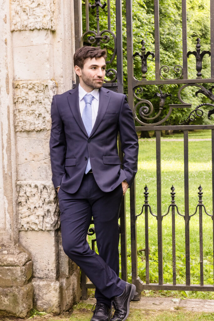 Groom portrait beside an ornate wrought-iron gate during an editorial Old Westbury Gardens engagement session.