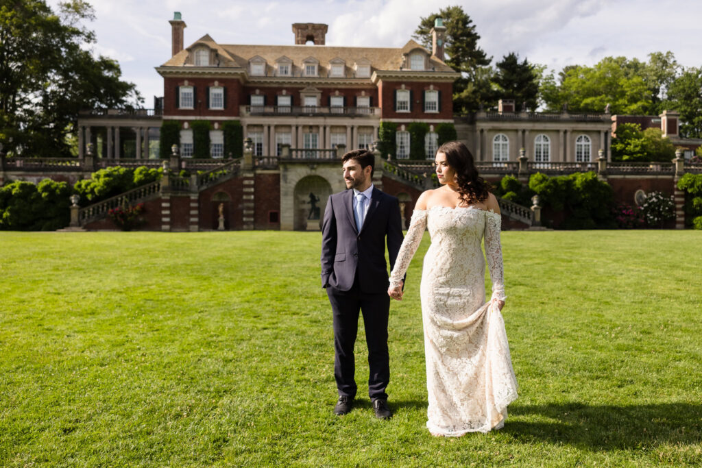 Couple holding hands in front of the mansion during an editorial Old Westbury Gardens engagement session.