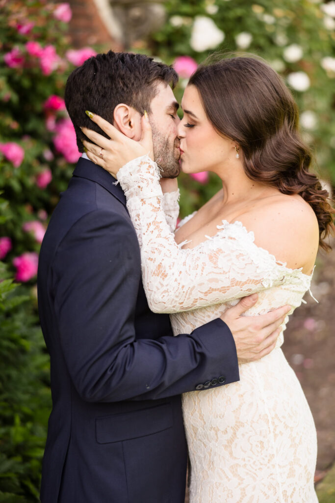 Close-up portrait of a couple kissing among blooming roses during an editorial Old Westbury Gardens engagement session.