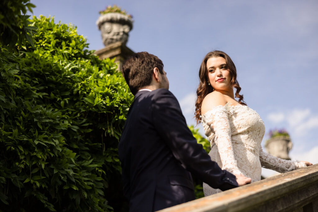 Editorial portrait of a couple on the estate staircase surrounded by greenery during an Old Westbury Gardens engagement session.