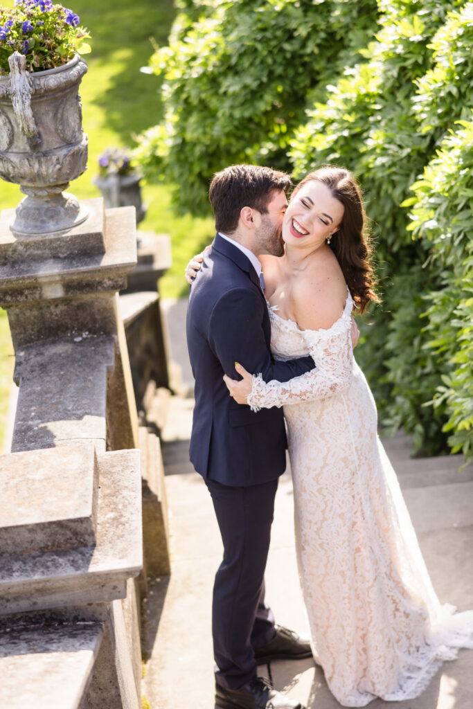 Joyful candid portrait of an engaged couple laughing together on the terrace during an editorial Old Westbury Gardens engagement session.