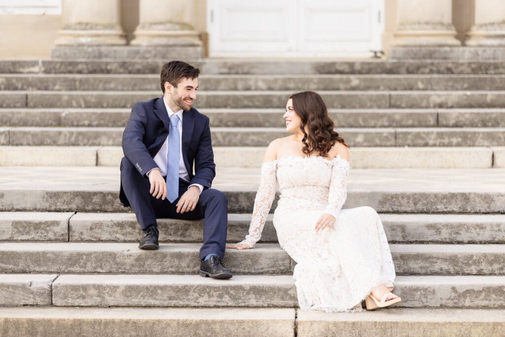 Couple sitting together on the estate staircase during an editorial Old Westbury Gardens engagement session.
