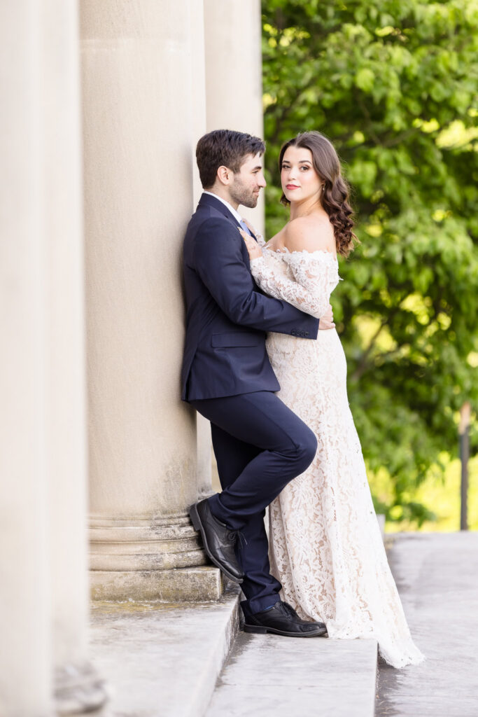 Couple embracing beside the stone columns of the mansion during an editorial Old Westbury Gardens engagement session.