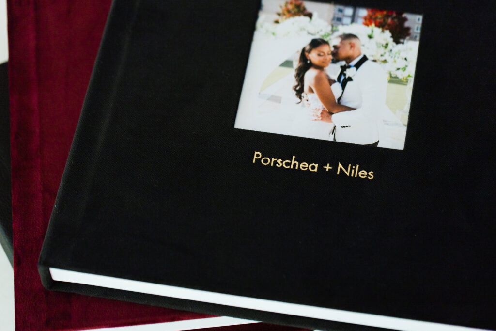 Black velvet wedding album with a custom cover photo and gold foil personalization.