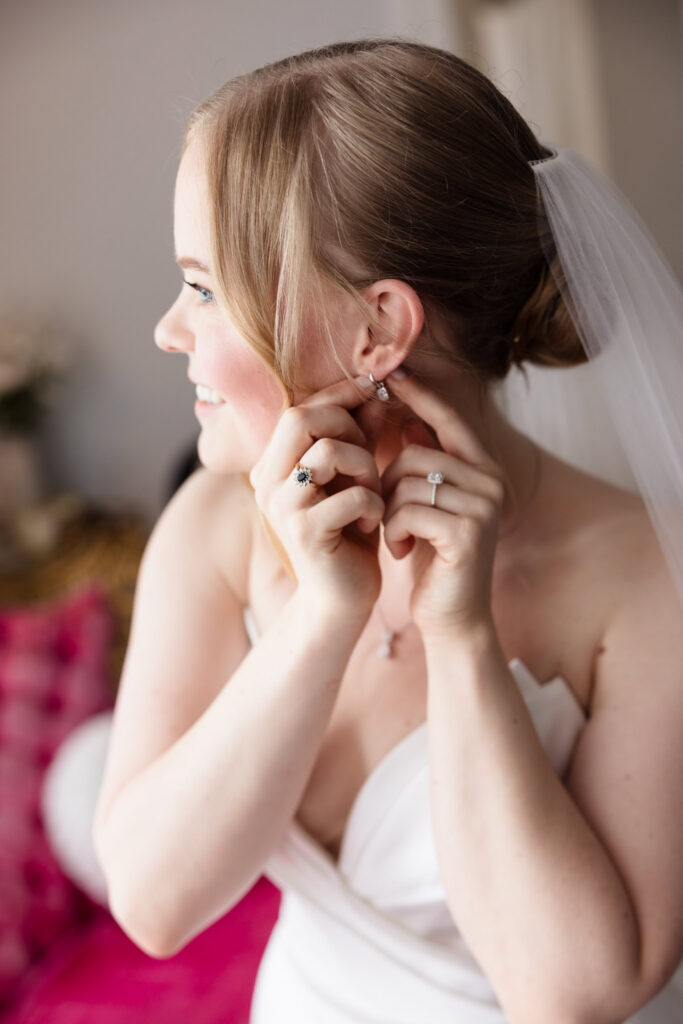 Lydia puts on her earrings while finishing her bridal look before her June wedding at Briarcliff Manor.