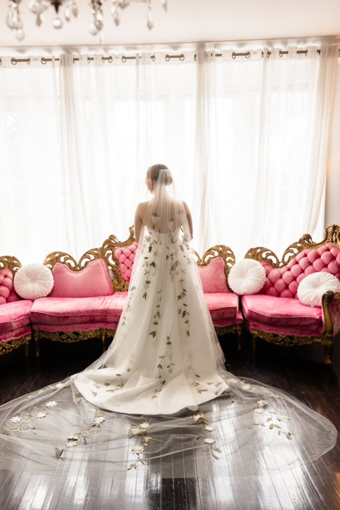 Lydia stands in front of the windows at Briarcliff Manor, showcasing her embroidered floral veil and Suzanne Neville wedding gown.