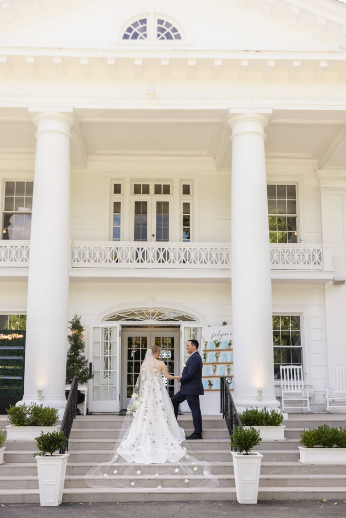 Lydia and Robbie stand together on the front steps of Briarcliff Manor with the venue's grand white columns behind them.