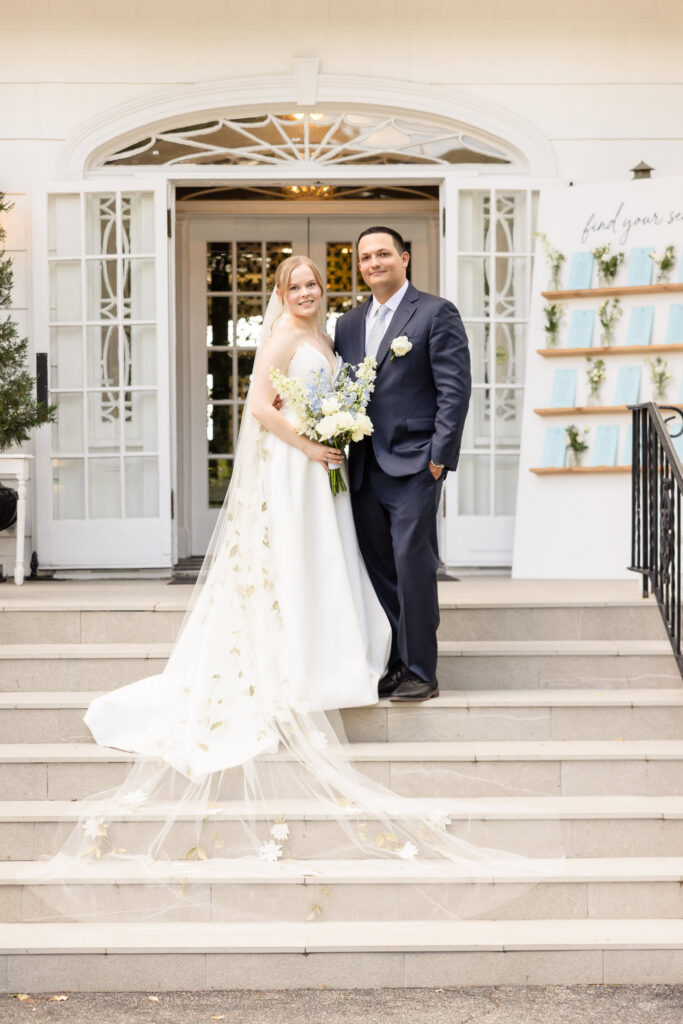 Lydia and Robbie pose with their bouquet on the entrance steps of Briarcliff Manor after their first look.