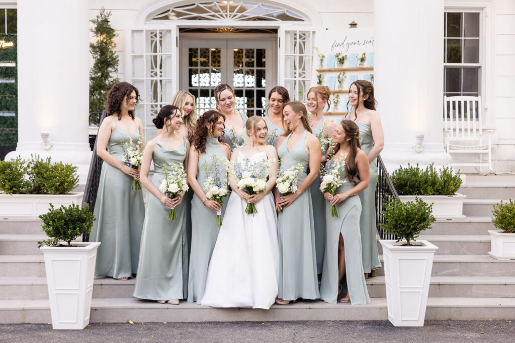 Bride surrounded by her bridesmaids on the front steps of Briarcliff Manor during formal wedding portraits.
