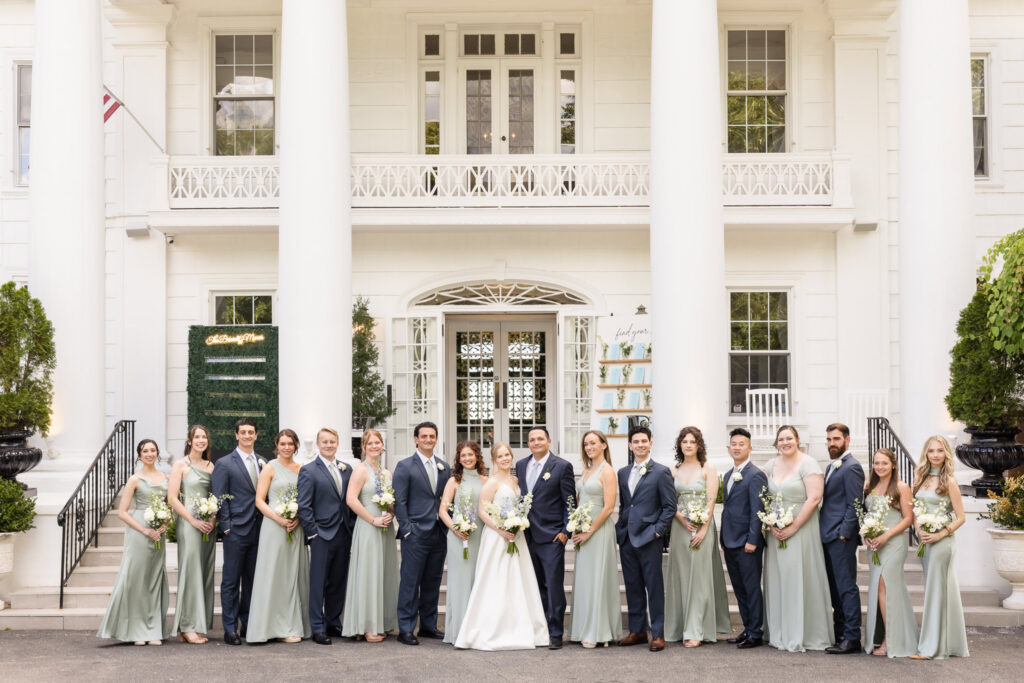 Full wedding party portrait featuring Lydia, Robbie, bridesmaids, and groomsmen on the front steps of Briarcliff Manor.
