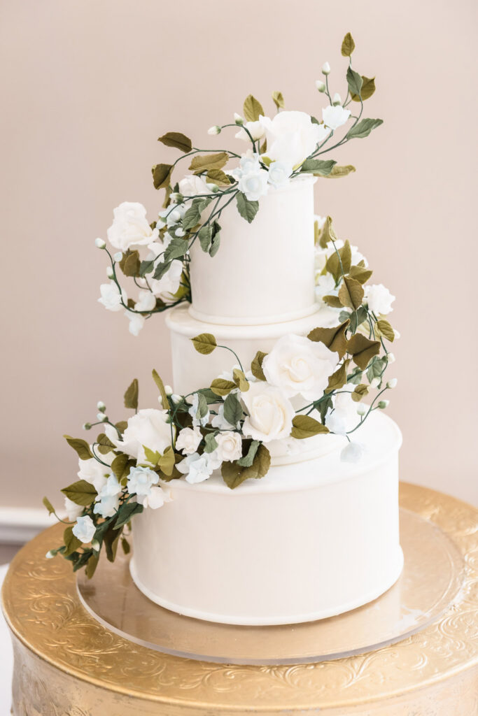 A modern white wedding cake decorated with cascading sugar flowers by Vici Design.