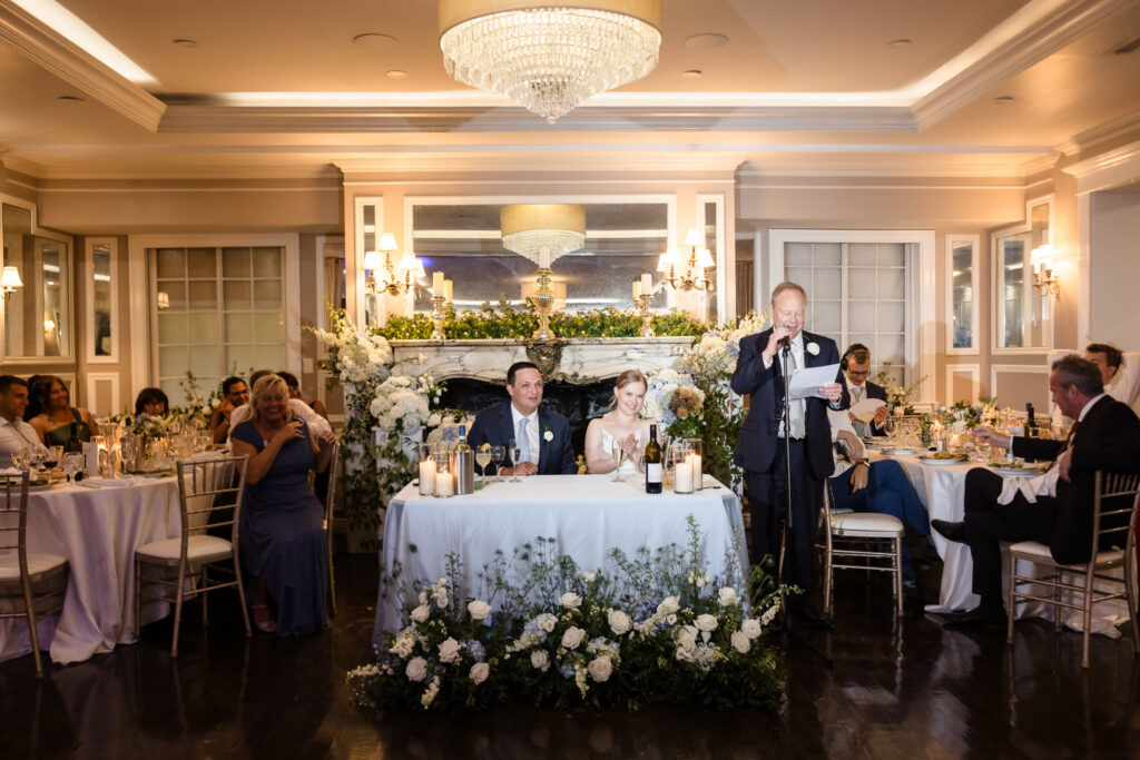 Lydia and Robbie listen as the bride's father gives an emotional toast during their reception.
