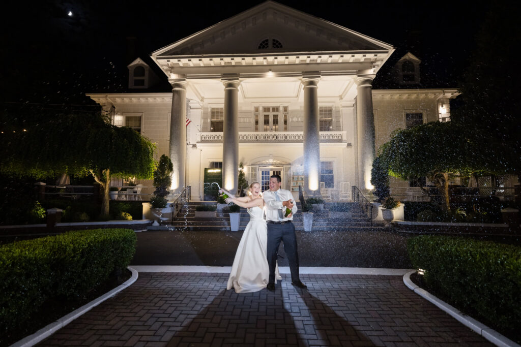 Lydia and Robbie celebrate with a champagne spray at night after their wedding reception.
