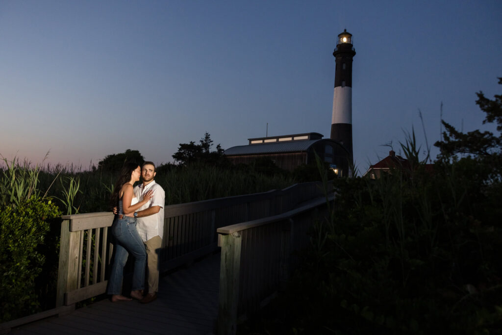 Catie and Zach embrace near the Fire Island Lighthouse during blue hour at the end of their Fire Island National Seashore engagement session.