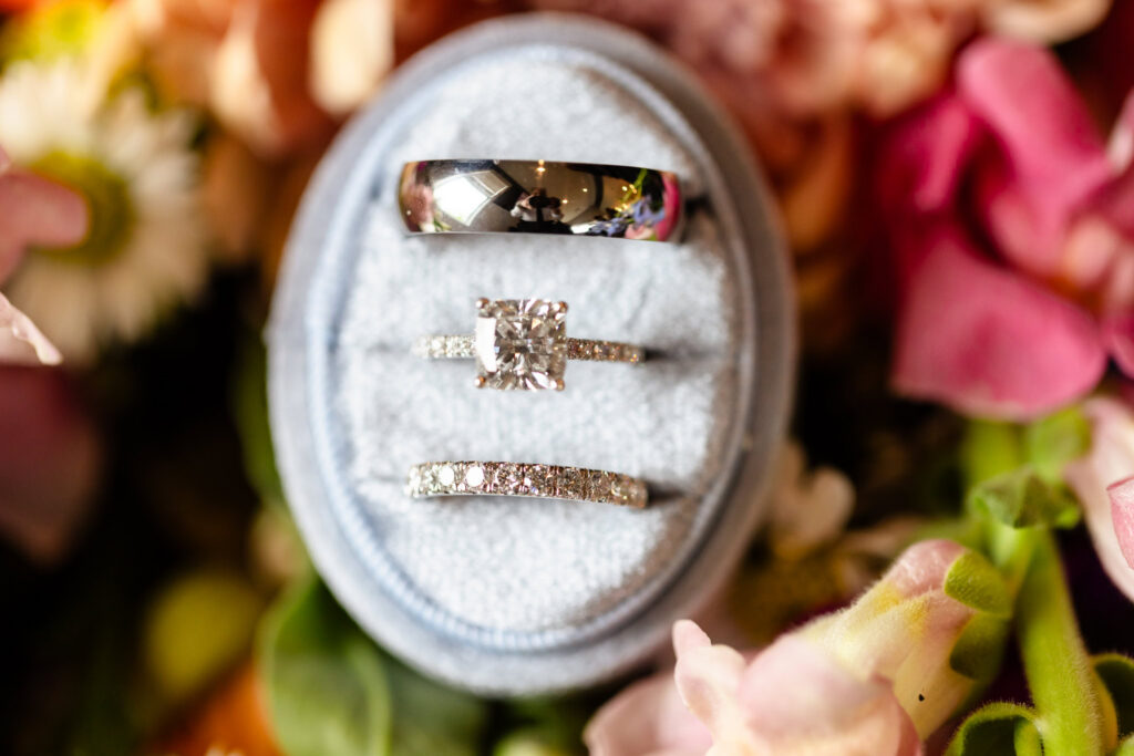 Wedding rings displayed in a velvet ring box with floral details during a Harbor Club at Prime wedding in Huntington, NY.