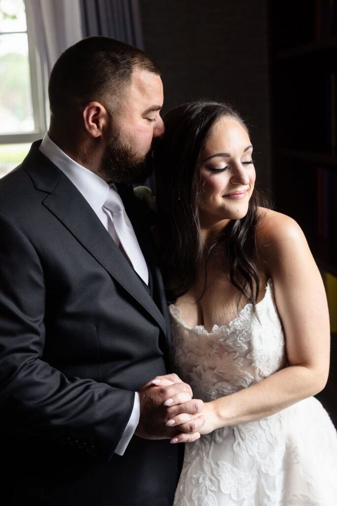 Groom kissing the bride's forehead during their intimate first look before the Harbor Club at Prime wedding.